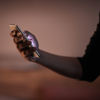Et nærbilde av en hånd som holder en mobiltelefon mens lyset skinner fra telefonskjermen