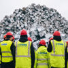Ryggtavlor av grupp med medarbetare på filial som tittar på materialhög