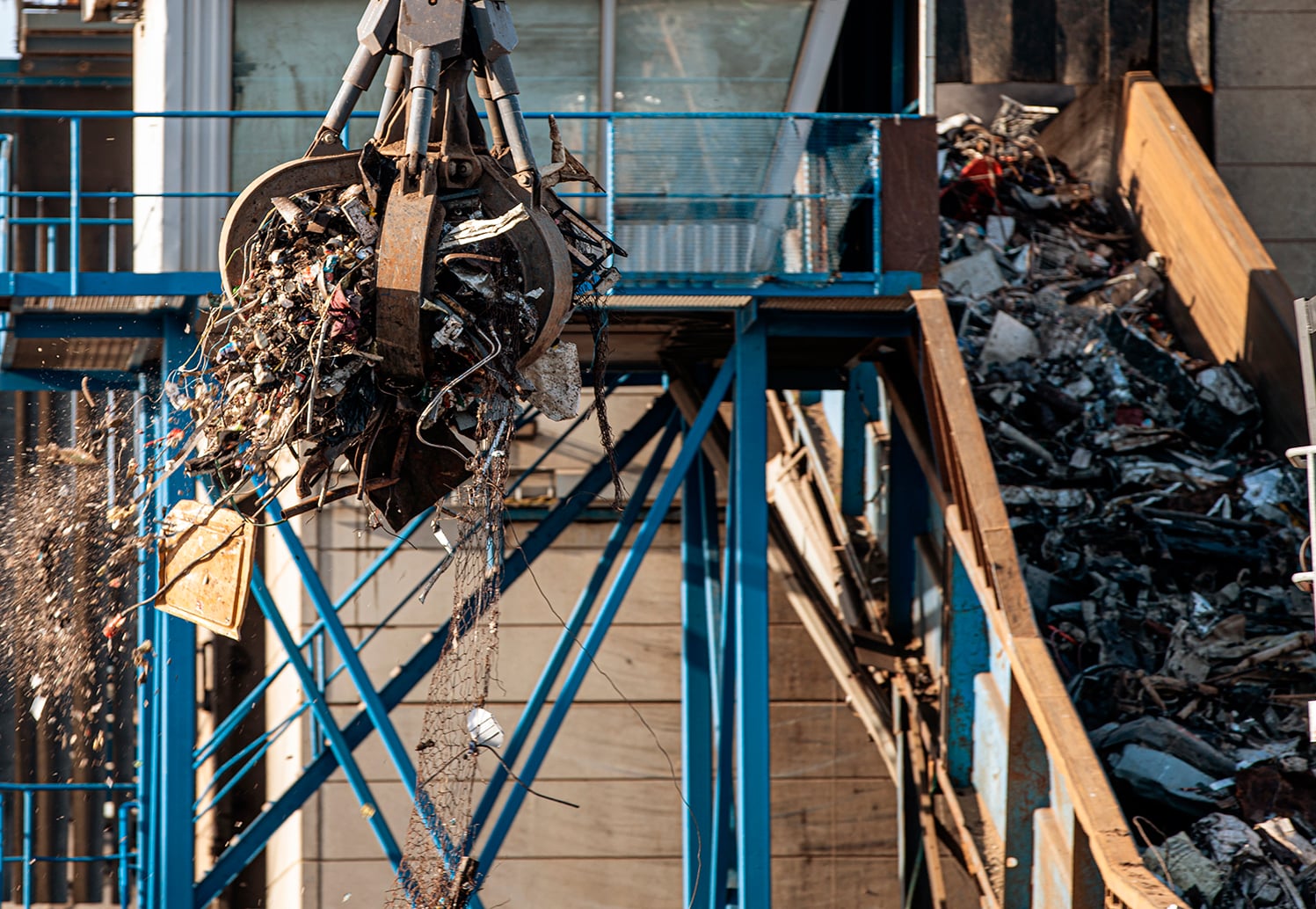 Materiaalikone nostaa metalliromua murskaimen hihnalle.