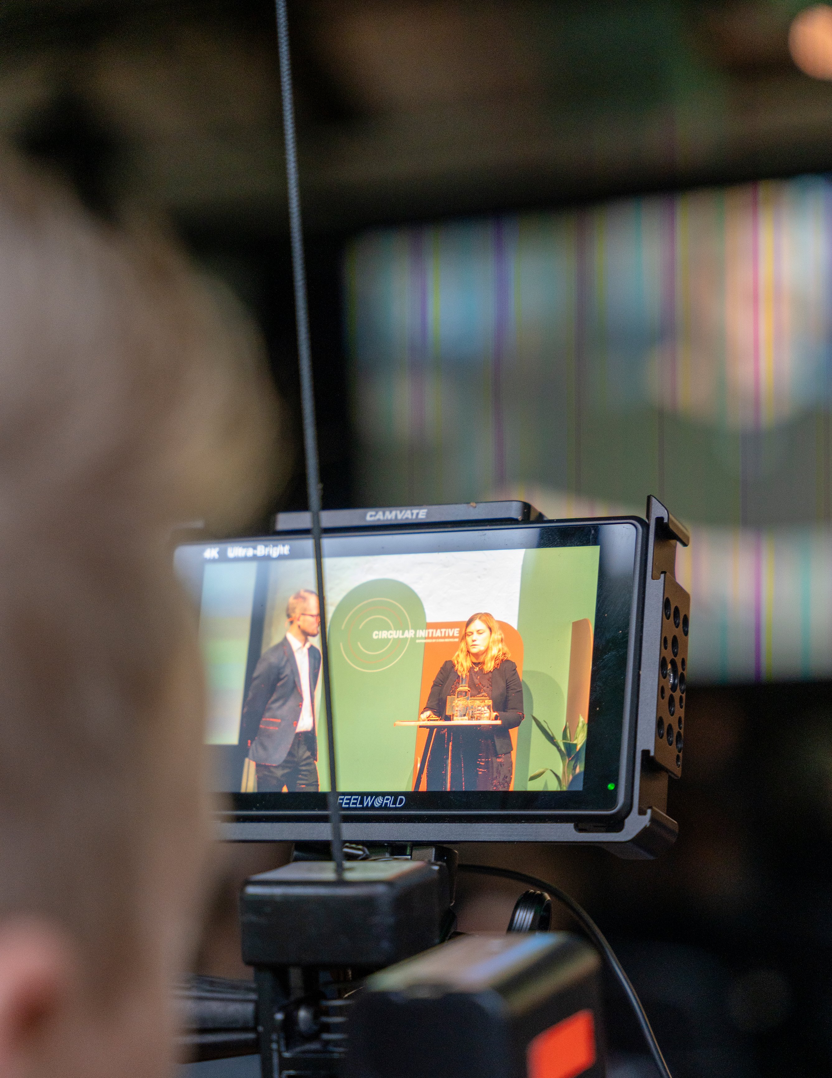 A view of Christoffer Muhl Pollari and Malin Candell speaking on stage at Circualr Initiative 2023, seen through a camera.