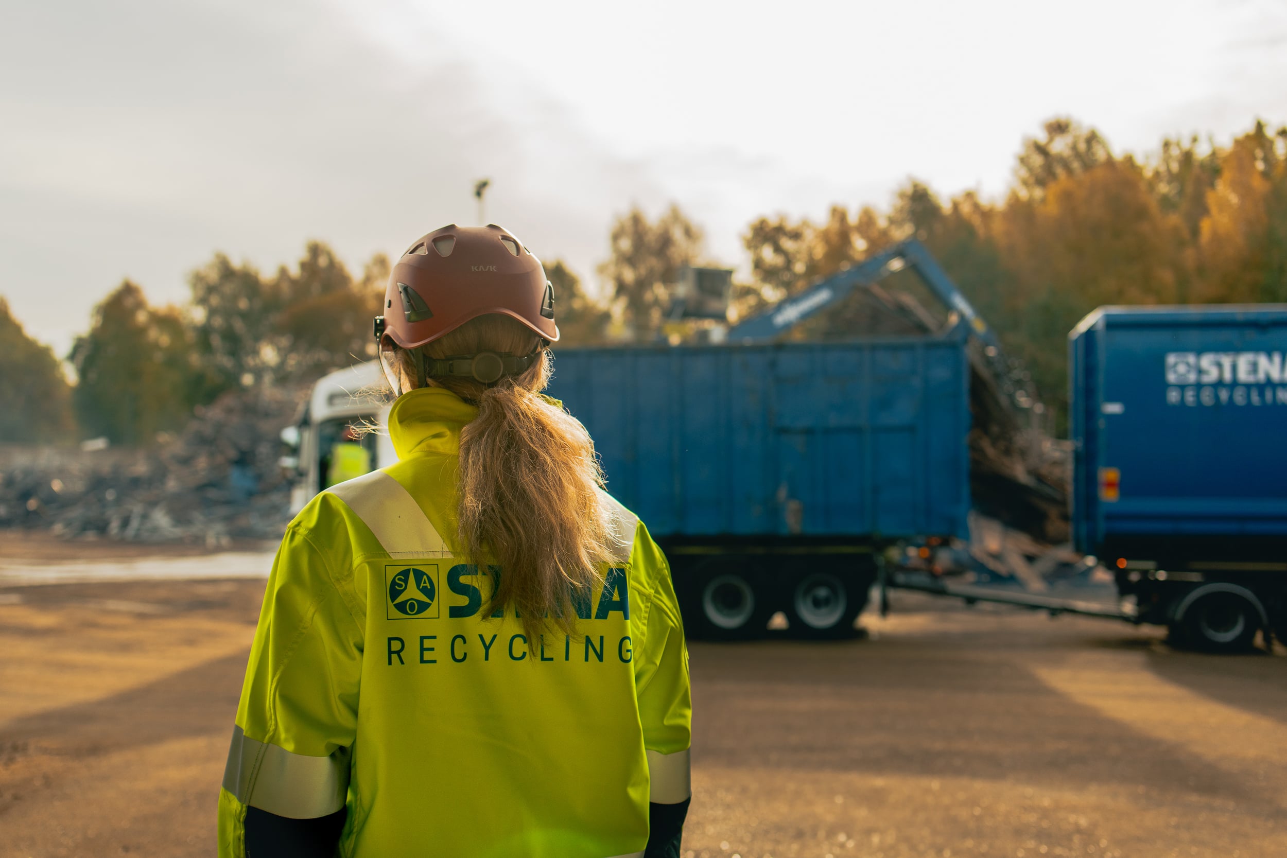 En Stena Recycling anställd i varselkläder vid blå container