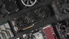 Various computer hardware components, including a graphics card, cooling fans, motherboard, hard drive, and RAM, arranged on a black surface.