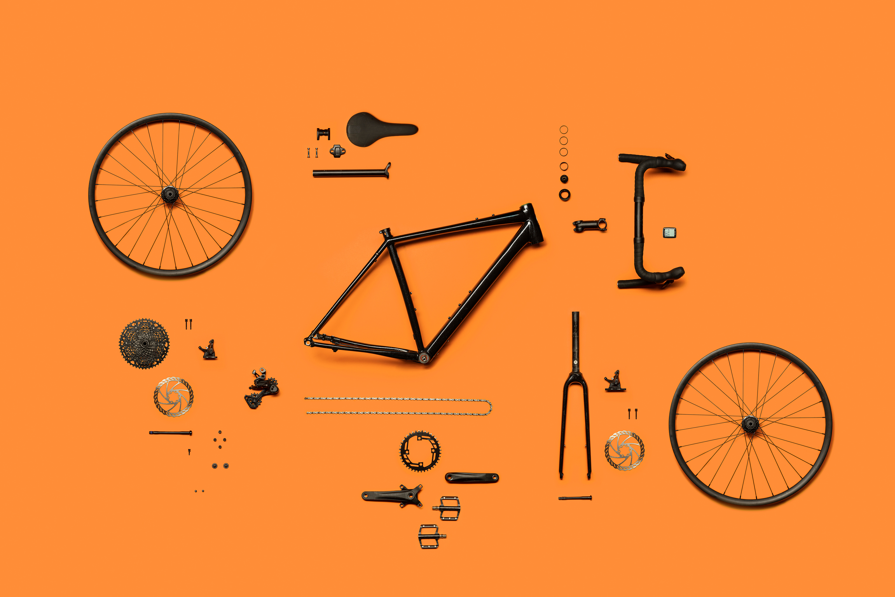 Disassembled bicycle parts neatly arranged on an orange background.