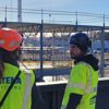 Två byggarbetare som tittar ut över ett bygge iklädda varselkläder och hjälm
