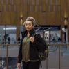 A young woman standing in a shopping centre stares directly into the camera