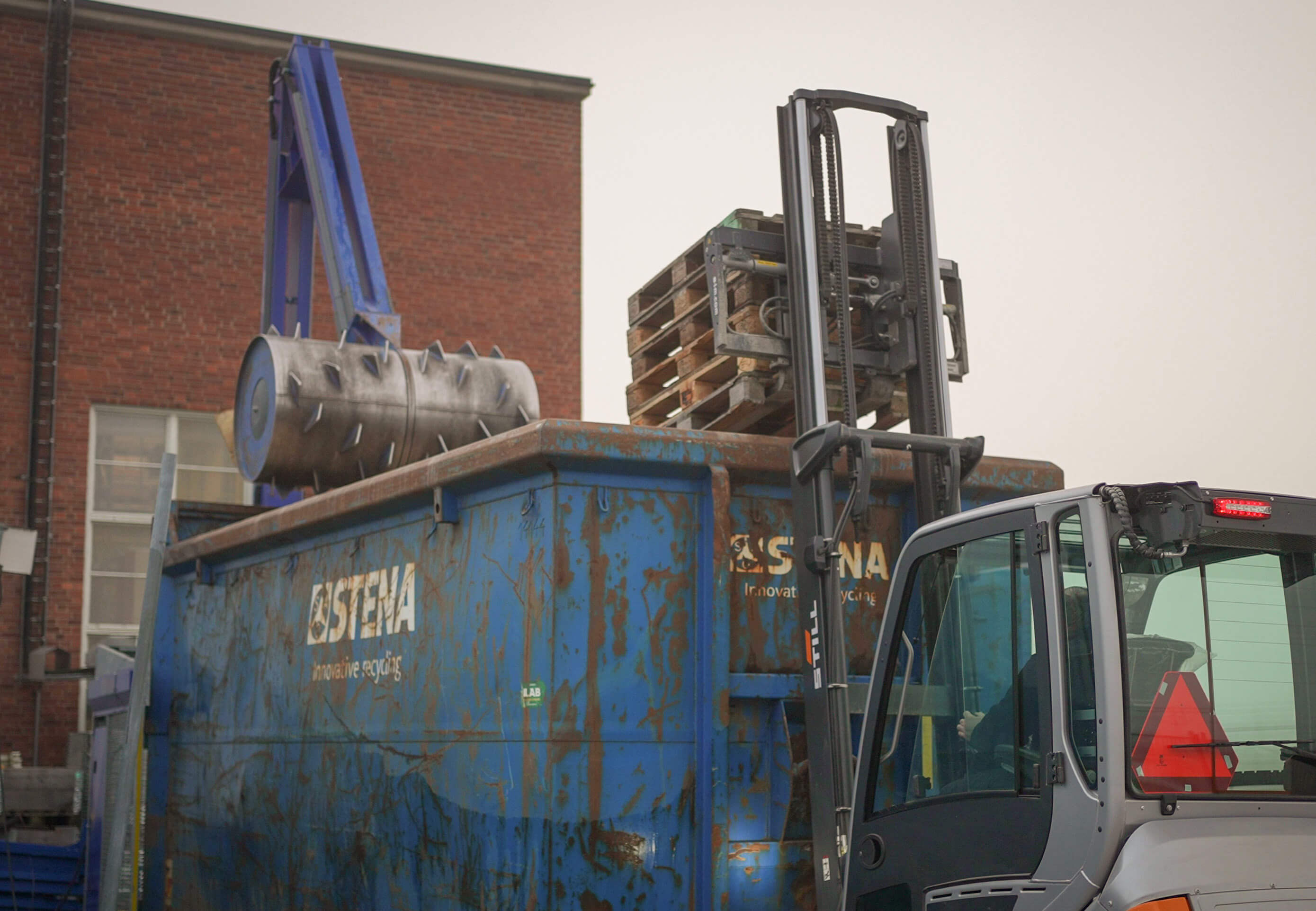 träpall lyfts in i container