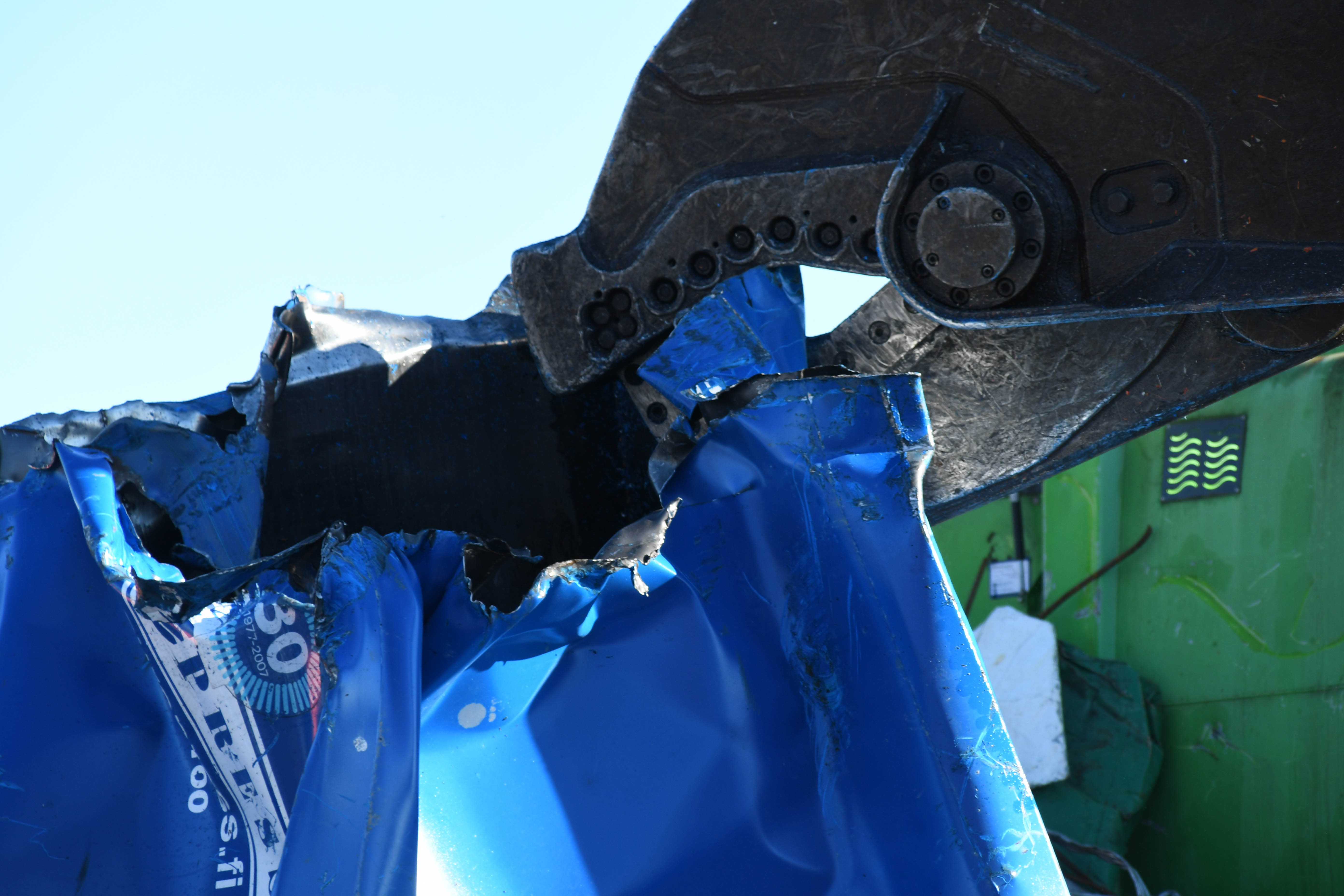 Vanha kierrätyslaite leikataan nokkaleikkurilla pieniksi paloiksi