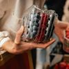 Person holding berries in plastic packaging