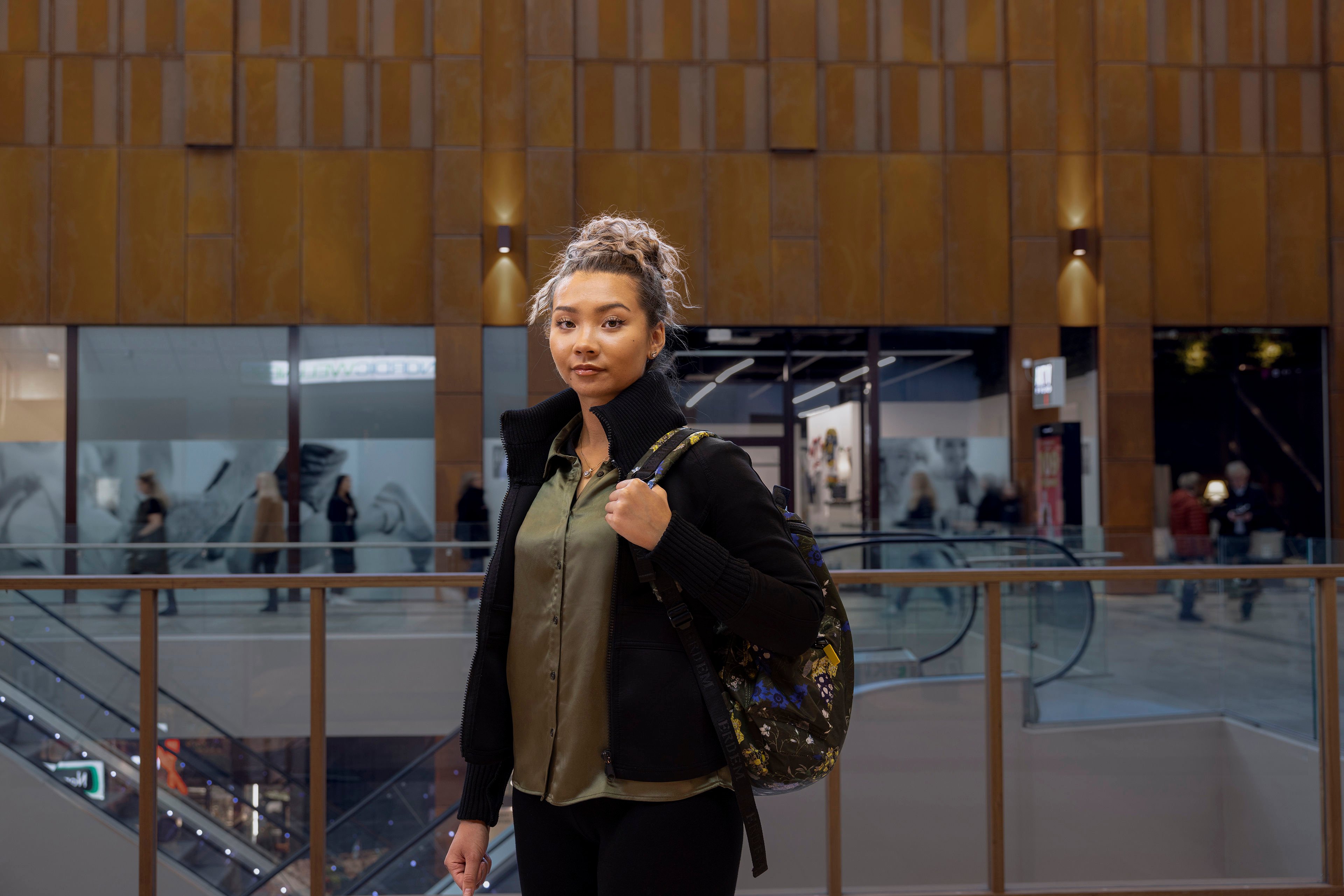 En ung kvinde, der står i et shoppingcenter, stirrer direkte ind i kameraet.