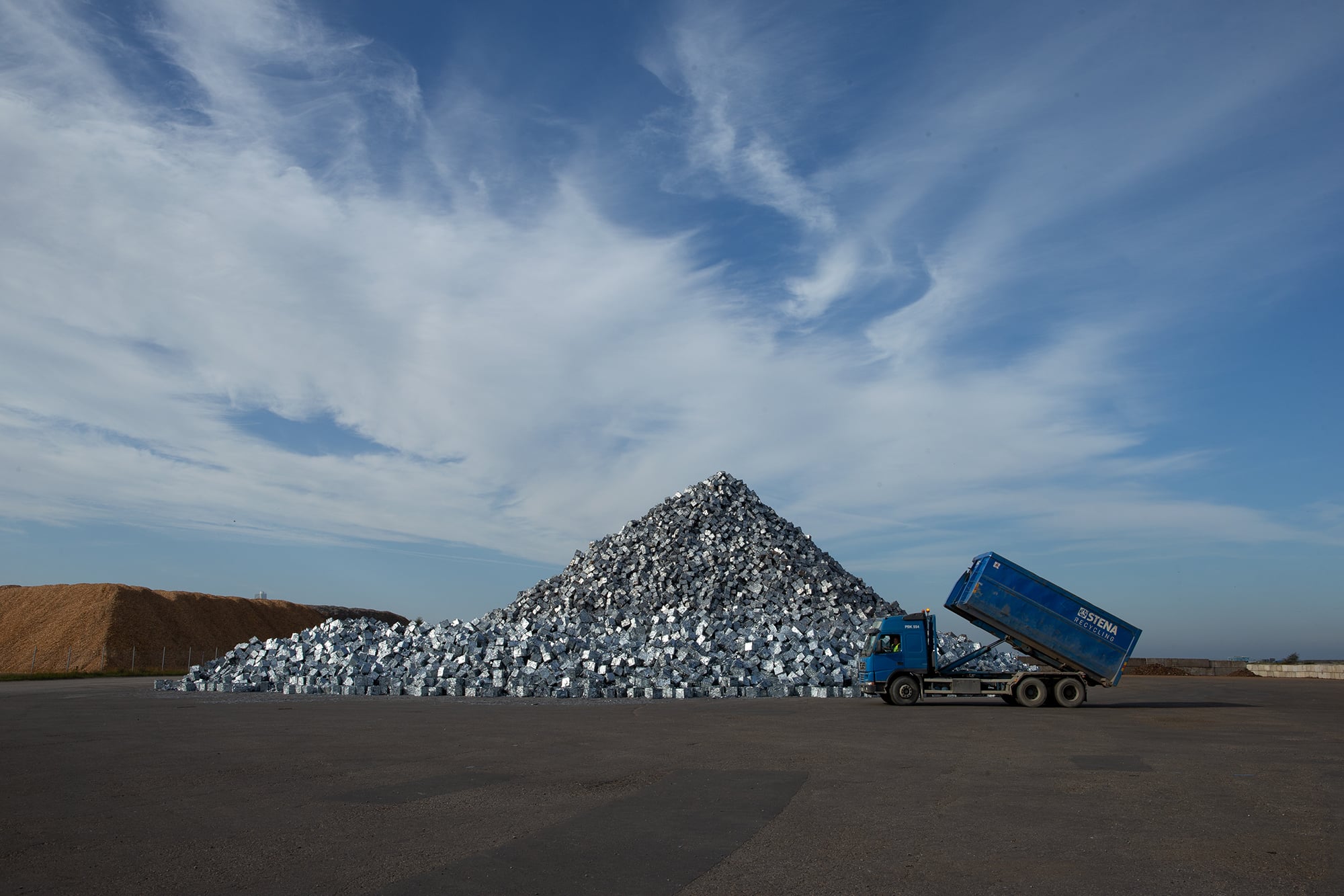 Bild på en stor hög med metall samt, en Stena Recycling lastbil