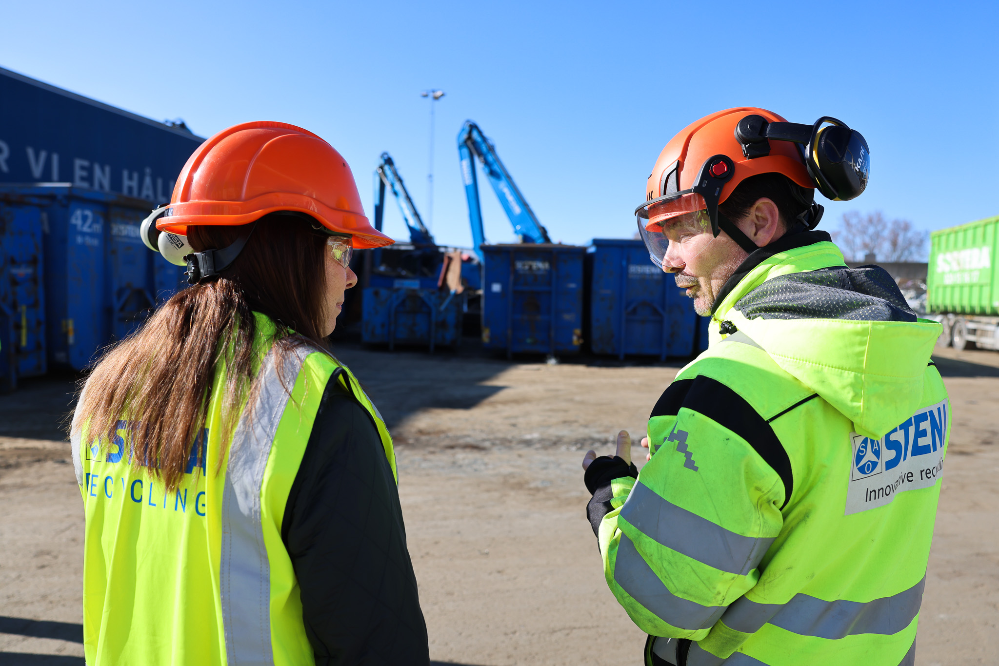 Två personer pratar klädda i varselkläder