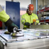 Two recycling experts dressed in reflective work jackets dismantling EV batteries