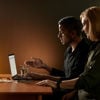 Two people working side by side sitting by a laptop