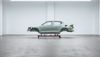 The body of a car sits raised in an empty warehouse