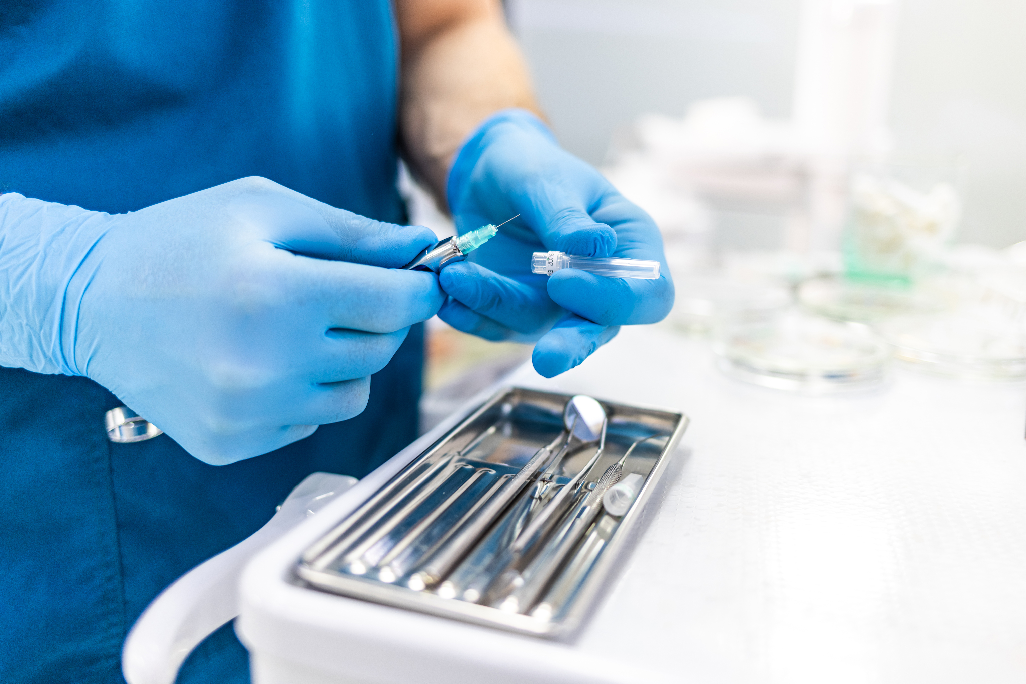 Närbild av en tandläkares händer som fyller en spruta