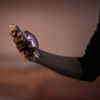 Nahaufnahme einer Hand, die ein Mobiltelefon hält, wobei das Licht auf dem Bildschirm des Telefons leuchtet
