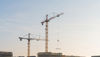 Silhouette of construction workers on top of a scaffolding, casting a concrete pillar