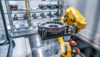 Braccio robotico industriale giallo che solleva un pezzo da lavorare in metallo fuso