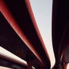 Three red motorway flyovers passing over a railway line. 