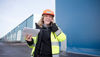 En smilende kvinnelig ansatt fra Stena Recycling i verneklær snakker i mobiltelefonen