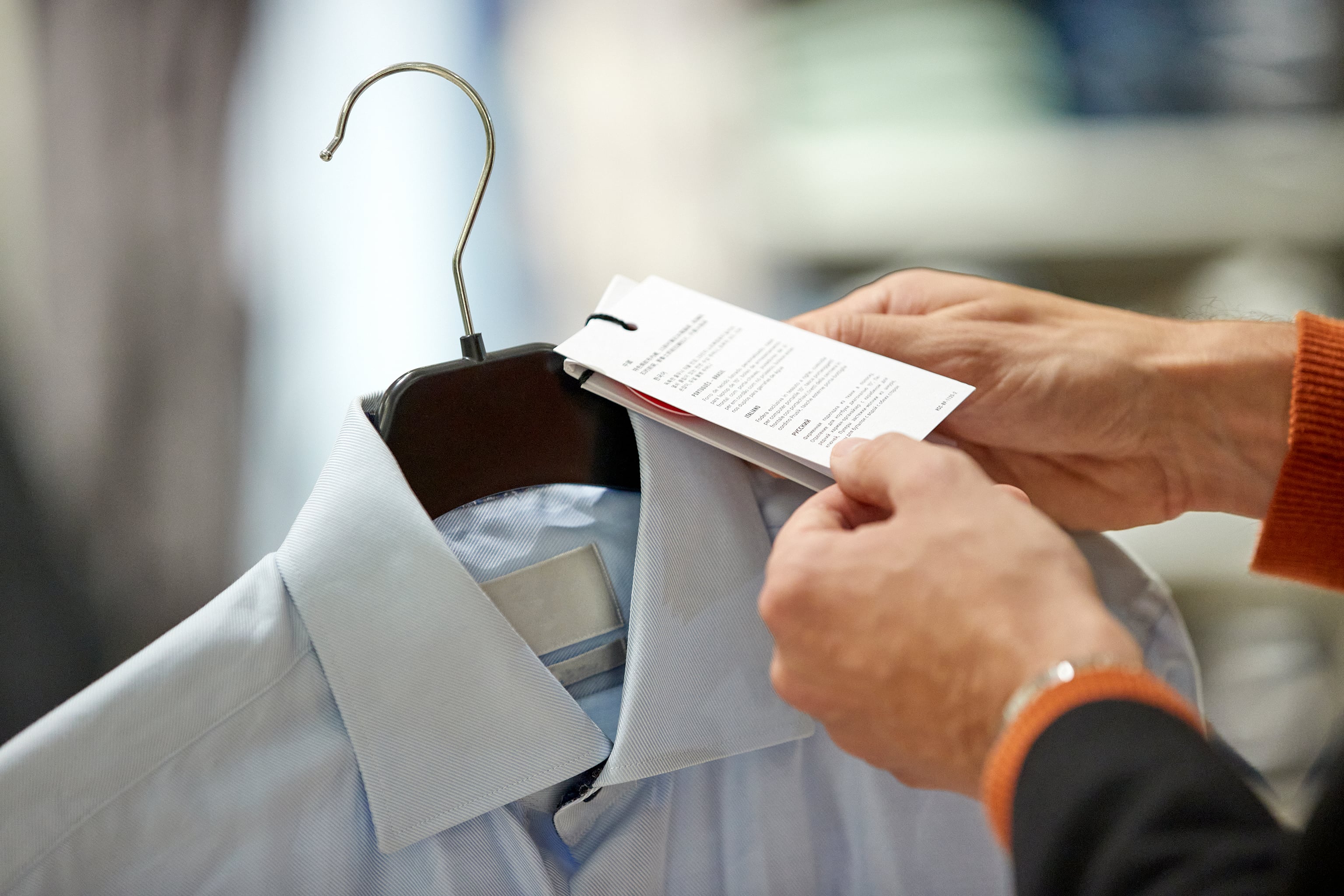A person holding the price tag for a blue collared shirt