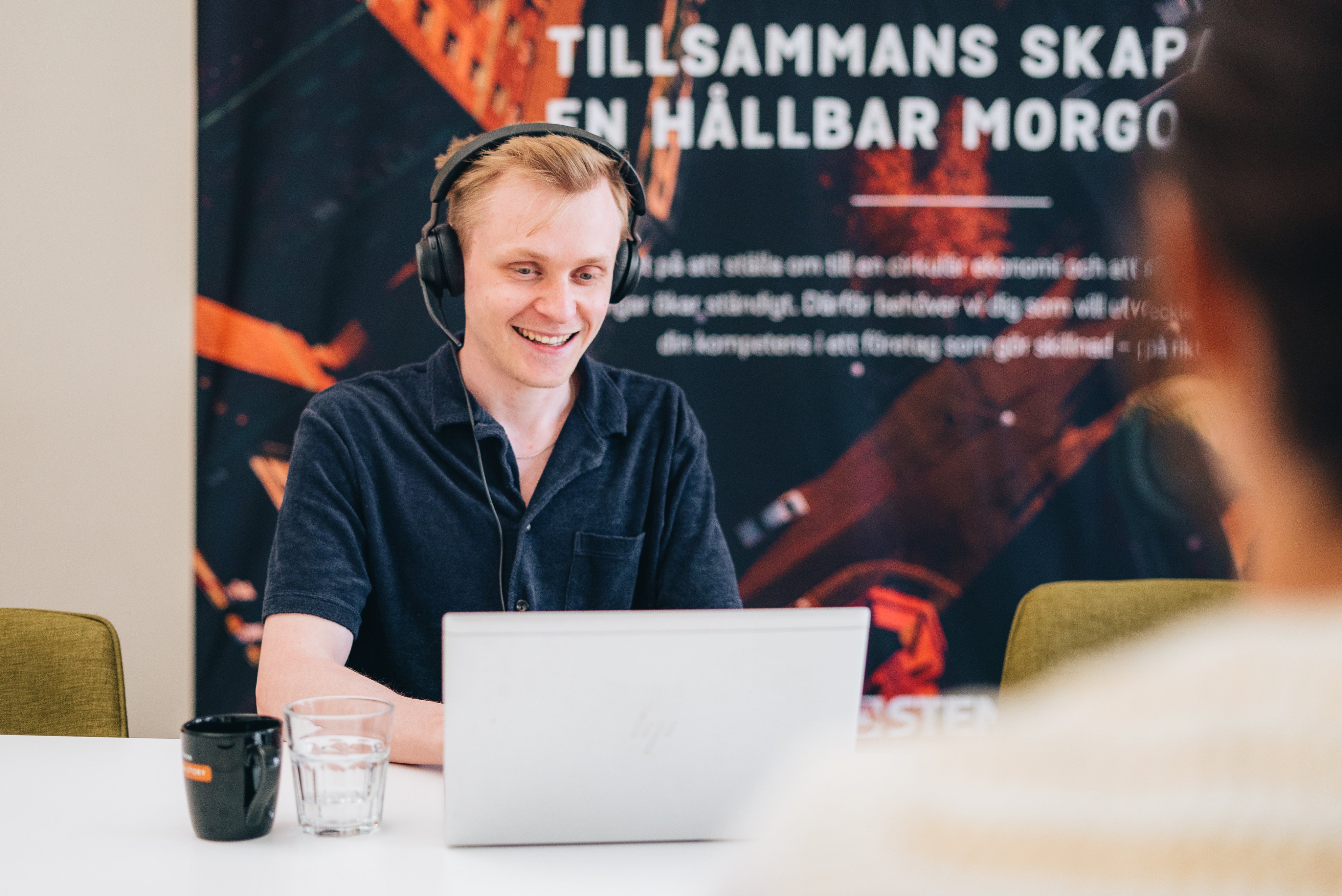 En person headset och laptop framför roströd bakgrund