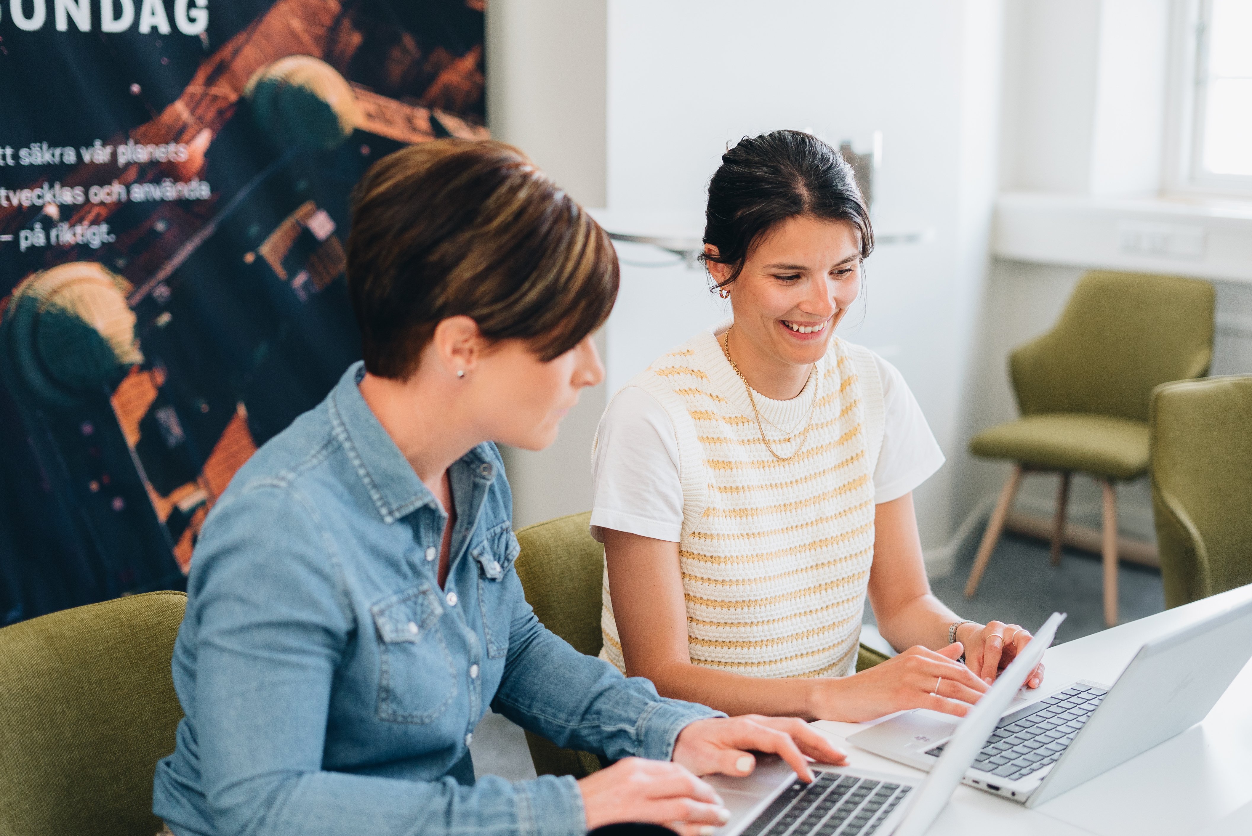 Två leende kvinnor framför laptop