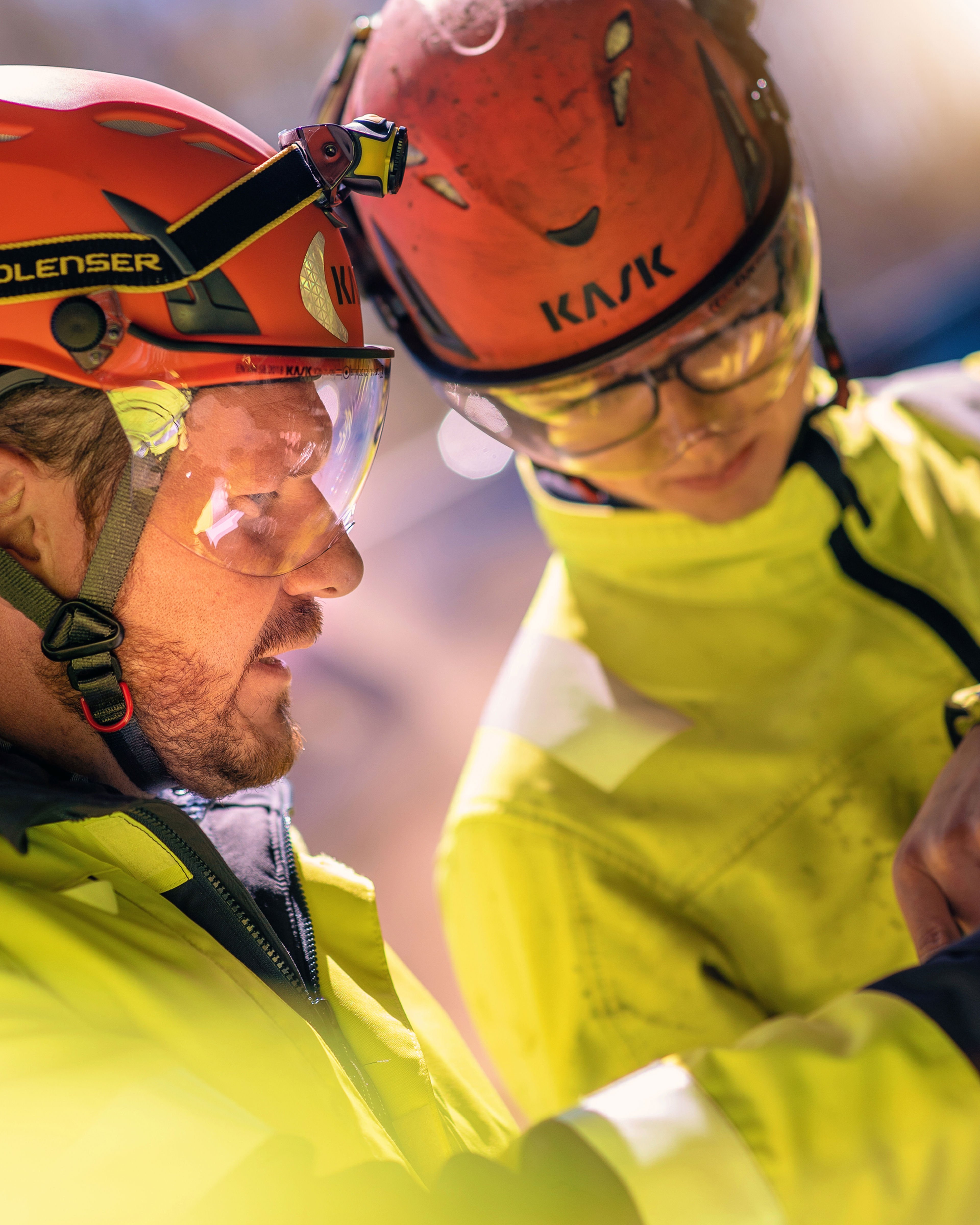 Two Stena Recycling experts dressed in hardhats and safety glasses, discussing safety advice.