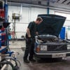 Man working on an old car in a workshop.