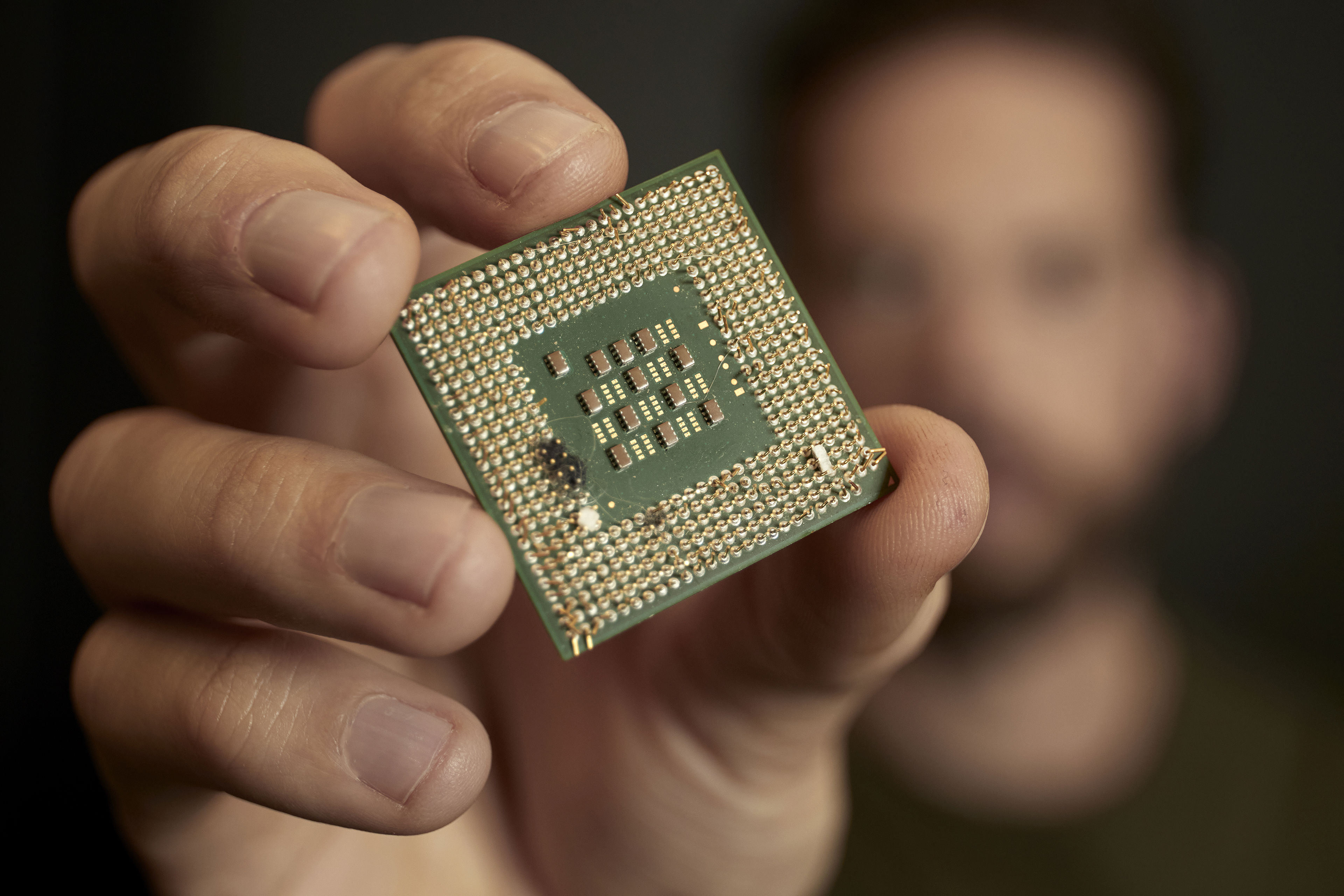 A close-up of a hand holding a piece of waste electronics