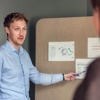 Tre kollegor som satt vid ett bord, fokuserade på sina bärbara datorer, engagerade sig i en professionell diskussion.